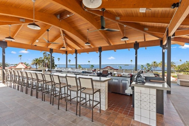 view of patio featuring a gazebo, ceiling fan, an outdoor bar, and a water view