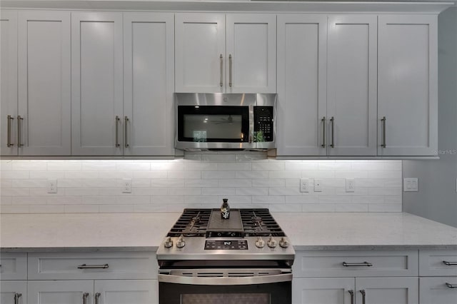 4899 Isola Ct, Wesley Chapel, FL 33543 - kitchen featuring appliances with stainless steel finishes, tasteful backsplash, and light stone counters