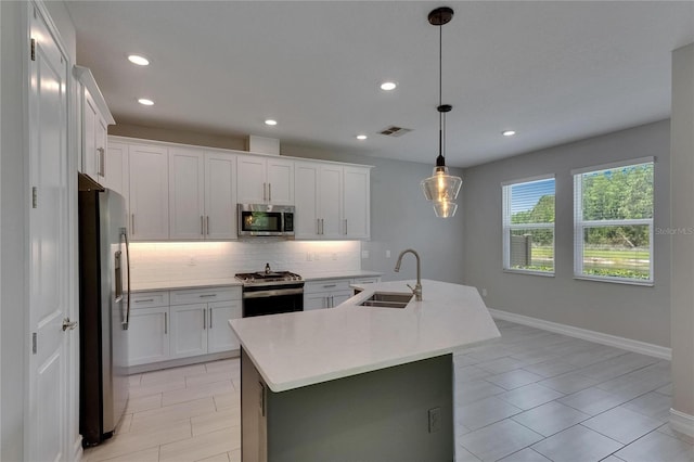 4899 Isola Ct, Wesley Chapel, FL 33543 - kitchen featuring a sink, stainless steel appliances, tasteful backsplash, light countertops, and white cabinetry