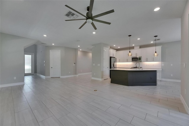 4899 Isola Ct, Wesley Chapel, FL 33543 - kitchen with stainless steel appliances, open floor plan, a ceiling fan, an island with sink, and a sink