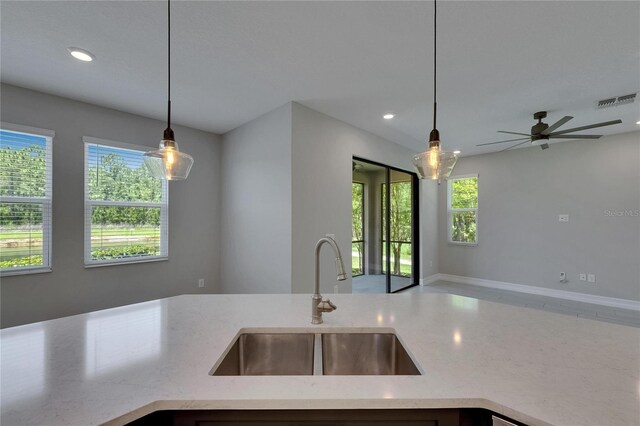 4899 Isola Ct, Wesley Chapel, FL 33543 - kitchen with a sink, light stone countertops, open floor plan, recessed lighting, and hanging light fixtures