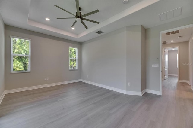 4899 Isola Ct, Wesley Chapel, FL 33543 - unfurnished room featuring ceiling fan, healthy amount of natural light, wood finished floors, a tray ceiling, and recessed lighting