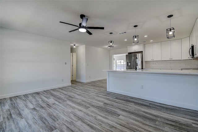 kitchen with appliances with stainless steel finishes, white cabinets, backsplash, and light hardwood / wood-style flooring