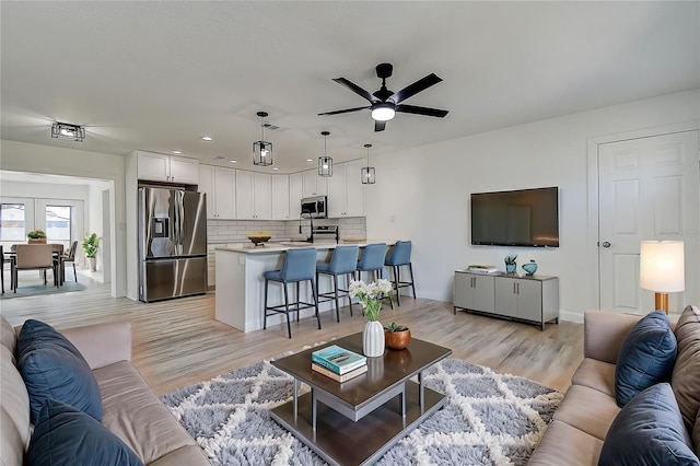 living room featuring sink, ceiling fan, and light wood-type flooring