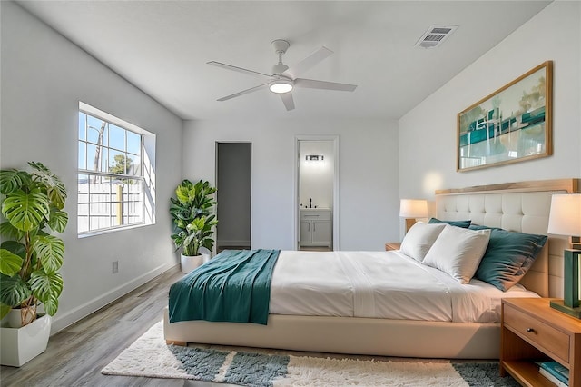 bedroom with ensuite bathroom, ceiling fan, and light hardwood / wood-style flooring