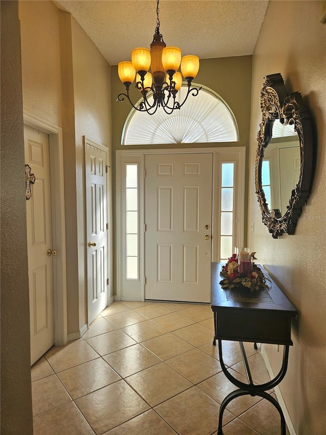 foyer entrance featuring a notable chandelier, a wealth of natural light, a textured ceiling, and light tile patterned flooring