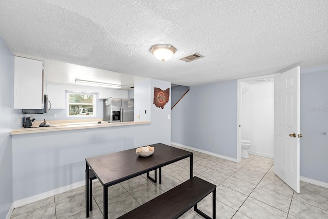 tiled dining space featuring a textured ceiling