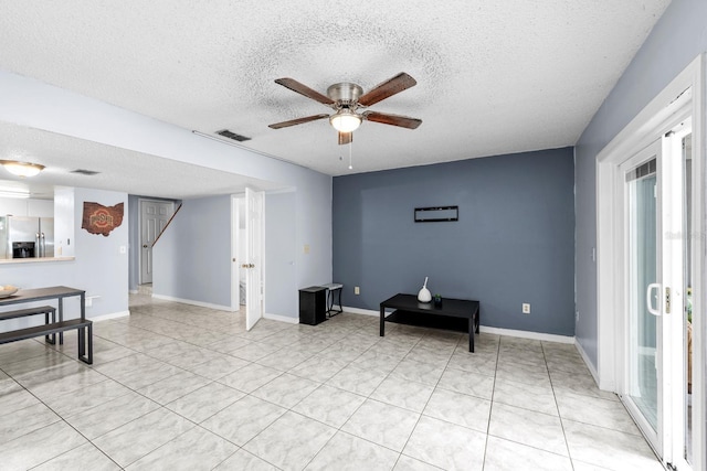 living area featuring a textured ceiling, ceiling fan, and light tile patterned flooring