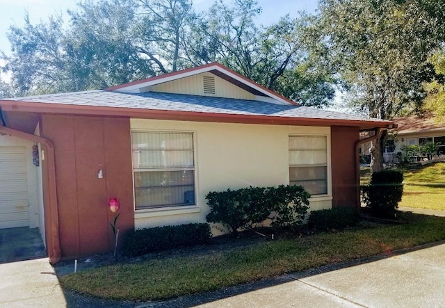 view of side of home featuring stucco siding and a shingled roof