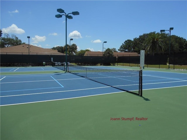 view of tennis court featuring community basketball court and fence