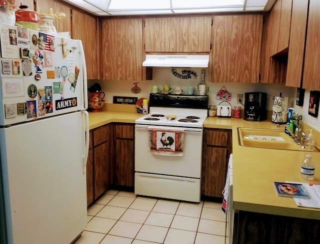 kitchen with white appliances, light countertops, under cabinet range hood, and a sink