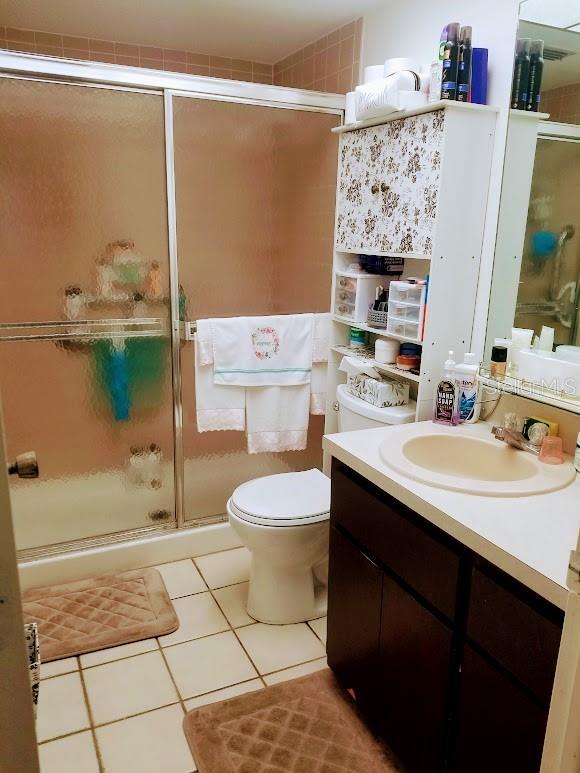 bathroom with vanity, tile patterned flooring, a shower with shower door, and toilet