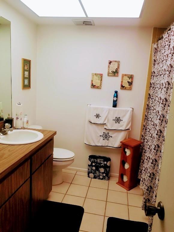 bathroom with tile patterned flooring, vanity, a skylight, and toilet