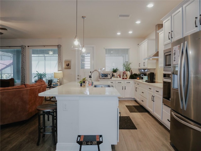 5709 Camila Song Ln, Tampa, FL 33625 - kitchen with appliances with stainless steel finishes, open floor plan, a sink, wall chimney range hood, and a kitchen bar