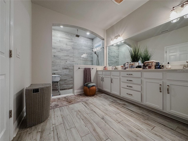 5709 Camila Song Ln, Tampa, FL 33625 - bathroom with double vanity, visible vents, walk in shower, and wood finished floors