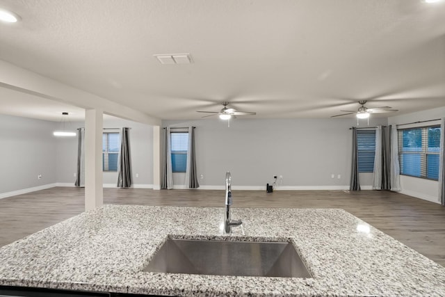 kitchen featuring ceiling fan, wood-type flooring, light stone countertops, and sink