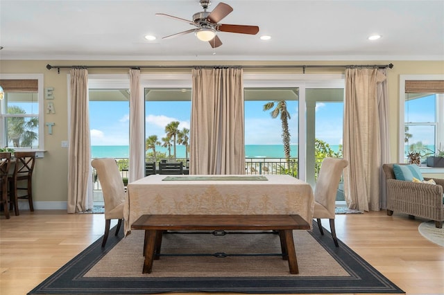 dining room featuring crown molding, a water view, ceiling fan, and light hardwood / wood-style floors