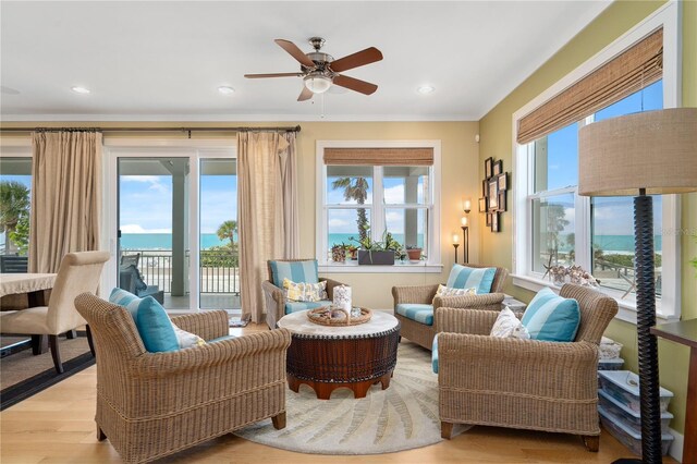 living room with ceiling fan, light wood-type flooring, a healthy amount of sunlight, and a water view