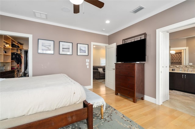 bedroom featuring ensuite bathroom, sink, a spacious closet, ceiling fan, and light hardwood / wood-style flooring