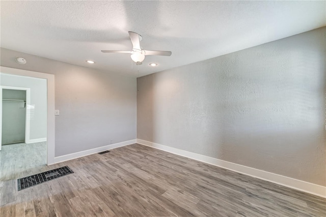 unfurnished room with ceiling fan, wood-type flooring, and a textured ceiling