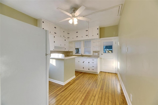 kitchen featuring white cabinetry, sink, white refrigerator, ceiling fan, and light hardwood / wood-style flooring