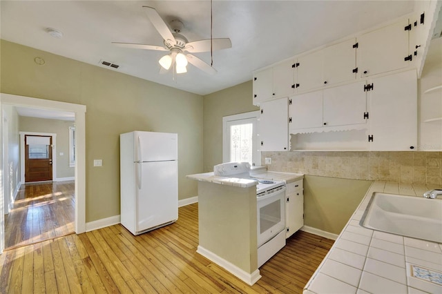 kitchen featuring tile countertops, sink, white cabinets, light hardwood / wood-style floors, and white appliances