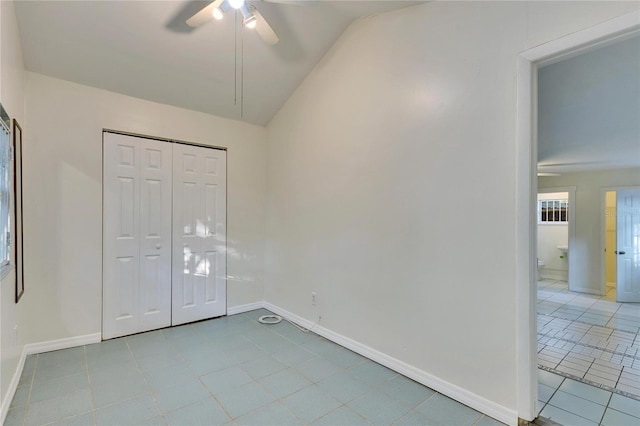 unfurnished bedroom featuring lofted ceiling, light tile patterned floors, ceiling fan, and a closet