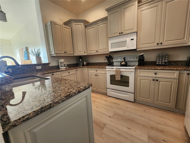 kitchen with sink, light wood-type flooring, kitchen peninsula, white appliances, and dark stone counters