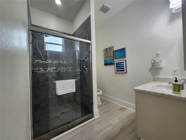 bathroom with vanity, toilet, a shower with door, and wood-type flooring