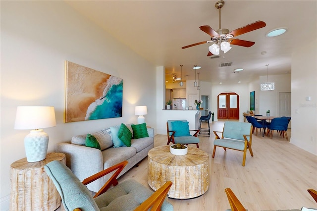 living room featuring ceiling fan, light wood-type flooring, and visible vents