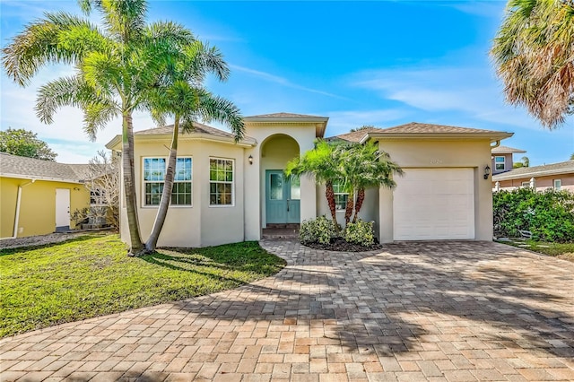 view of front of home with stucco siding, driveway, a front yard, and an attached garage