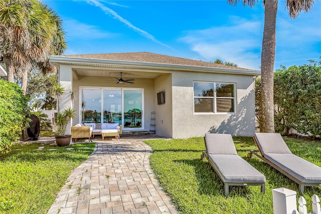 rear view of property with stucco siding, a shingled roof, a lawn, a patio area, and ceiling fan