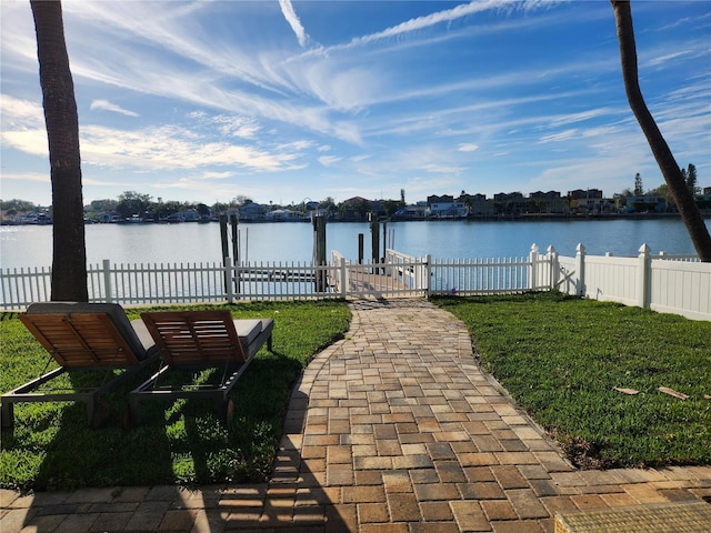 view of yard with a boat dock, a water view, and fence