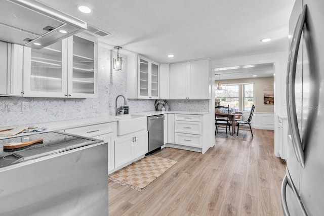 kitchen featuring extractor fan, decorative light fixtures, white cabinetry, stainless steel appliances, and light hardwood / wood-style flooring