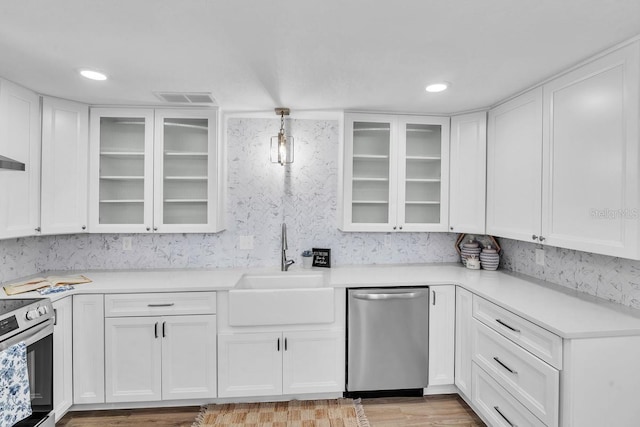 kitchen featuring stainless steel appliances, white cabinetry, sink, and pendant lighting