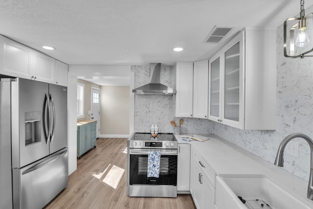 kitchen with white cabinets, stainless steel appliances, and wall chimney range hood