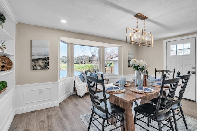 dining room featuring an inviting chandelier, a textured ceiling, and light hardwood / wood-style floors