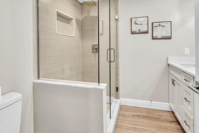 bathroom with walk in shower, vanity, toilet, and wood-type flooring