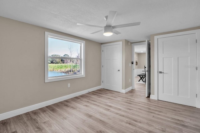 unfurnished bedroom with ceiling fan, light wood-type flooring, and a textured ceiling