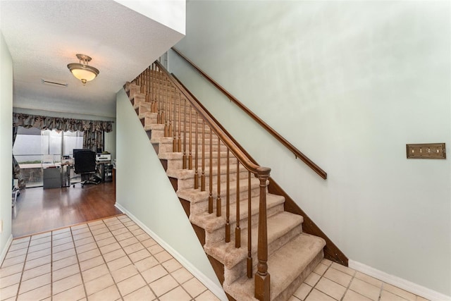 stairs with tile patterned floors and a textured ceiling