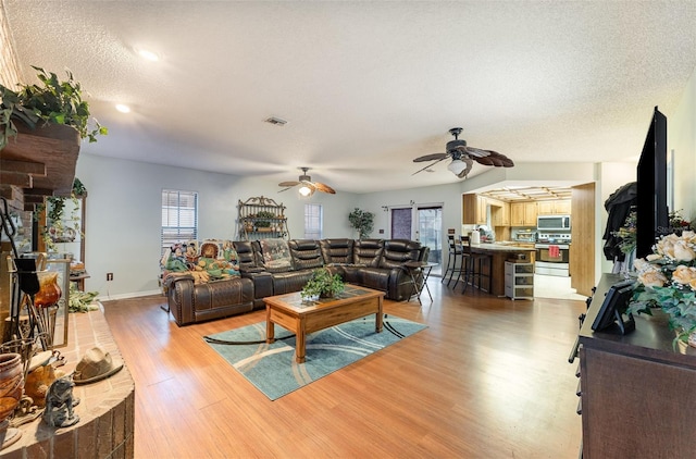 living room featuring ceiling fan, wood-type flooring, and a textured ceiling