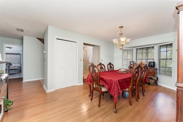 dining room with light hardwood / wood-style flooring, a chandelier, and a textured ceiling