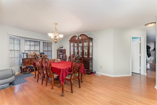 dining room featuring a chandelier, a textured ceiling, and light wood-type flooring