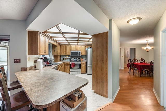 kitchen with stainless steel appliances, a kitchen breakfast bar, kitchen peninsula, and decorative light fixtures