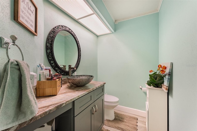 bathroom with crown molding, wood-type flooring, vanity, and toilet