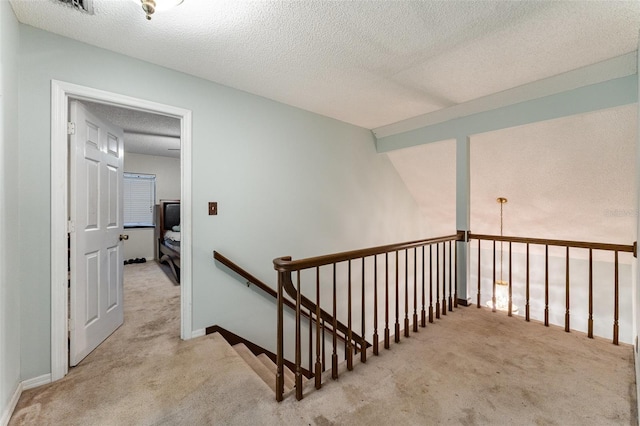 staircase featuring carpet flooring, vaulted ceiling, and a textured ceiling