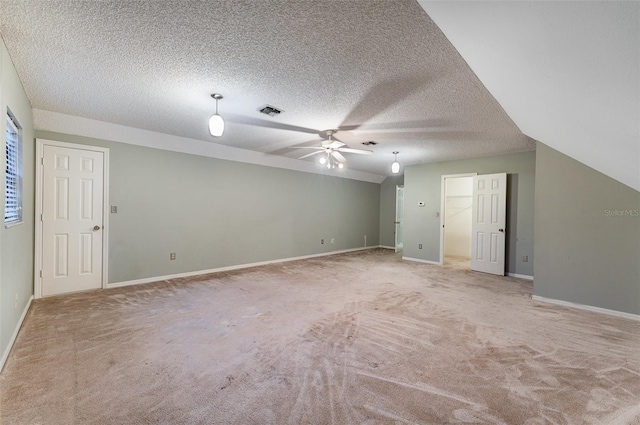 interior space featuring ceiling fan, light colored carpet, vaulted ceiling, and a textured ceiling