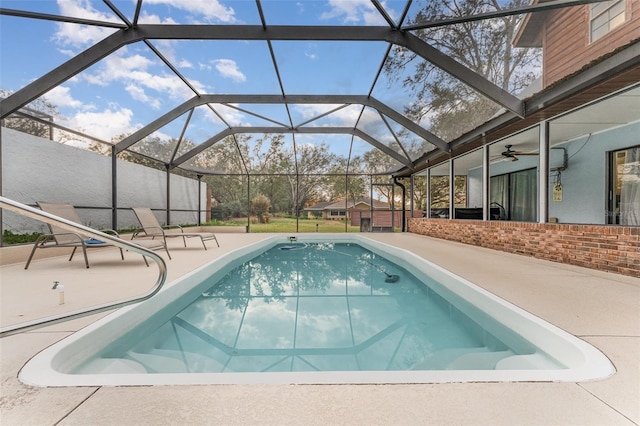 view of swimming pool with a patio, ceiling fan, and glass enclosure