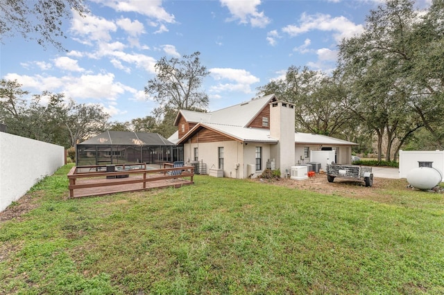 rear view of property with a pool side deck, a yard, and glass enclosure