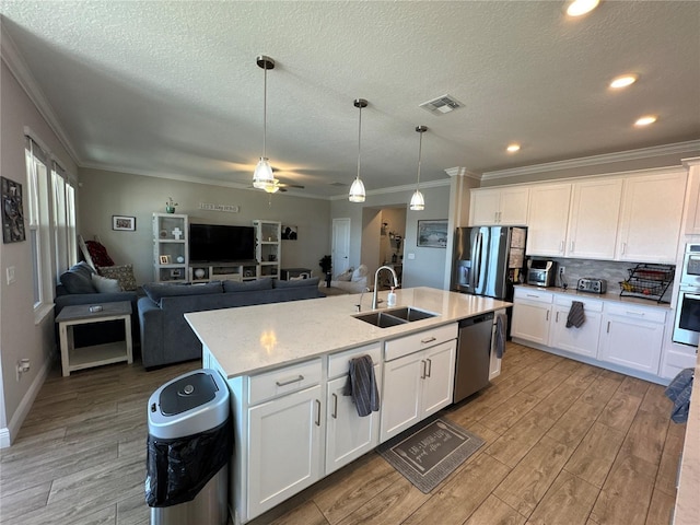 kitchen with stainless steel appliances, white cabinetry, sink, and an island with sink